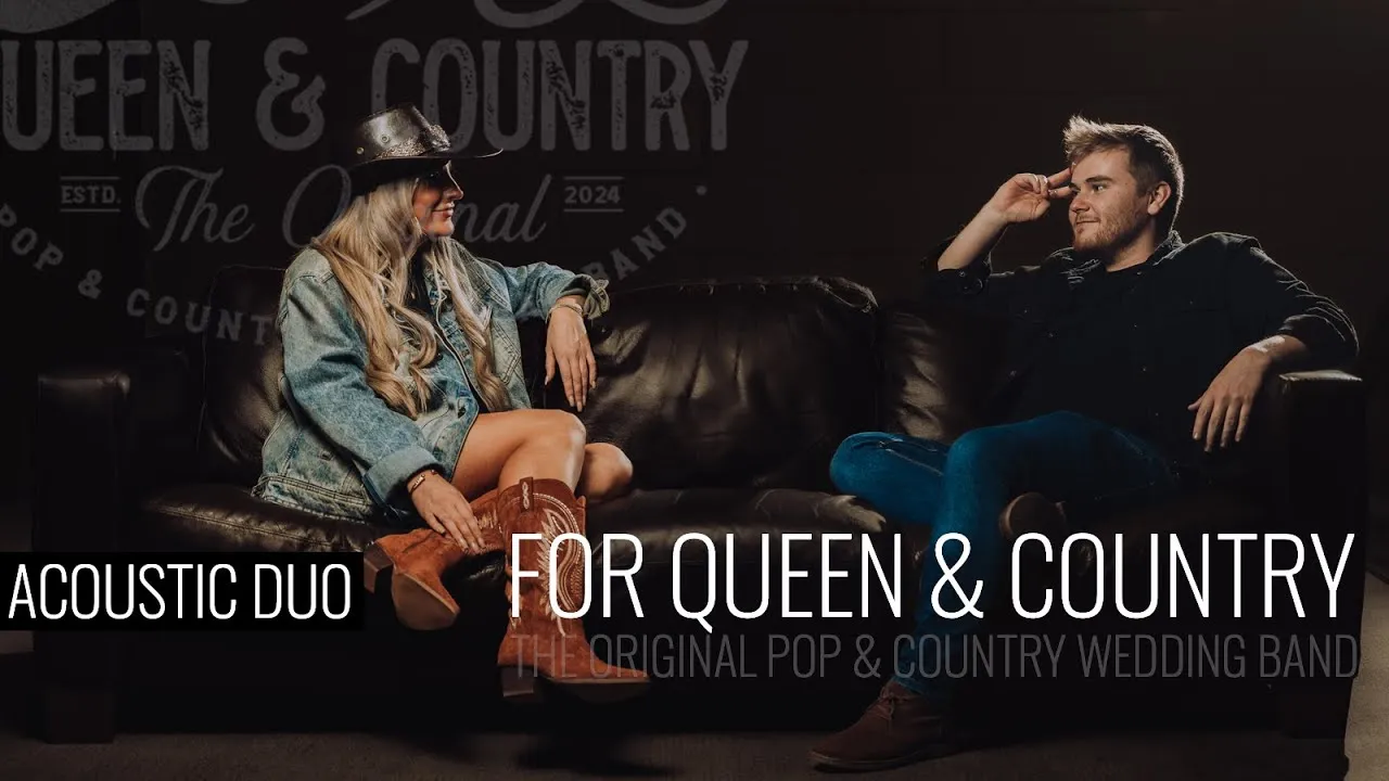 Man and woman sitting on a dark leather couch, promoting acoustic duo For Queen & Country, a pop and country wedding band.